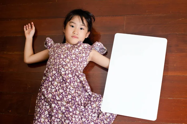 Pequena Criança Asiática Deitada Fundo Madeira Com Uma Placa Branca — Fotografia de Stock