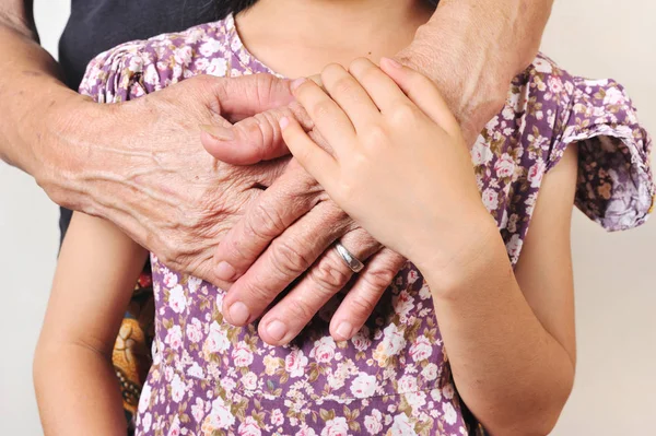 hand of senior hugging with her child. hand of a child embrace the hands of an old woman with lov