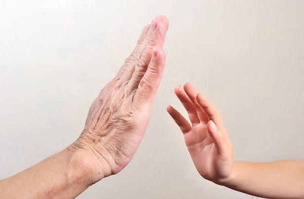 child\'s hand try to touch senior hand  or old woman hand. Two different generations concept.