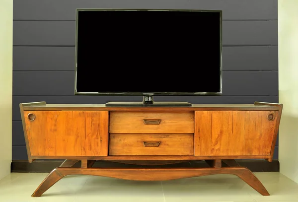 Teak retro television cabinet in room against dark wall