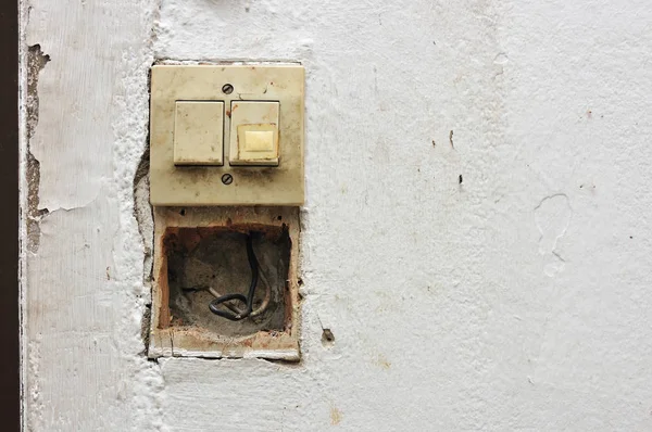 a light switch and electrical socket switch with damaged wiring on the wall