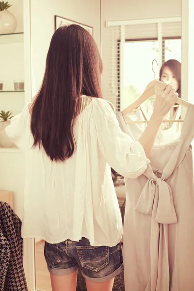 鏡の前で服を選ぶ若いアジア女性 ロイヤリティフリーのストック画像