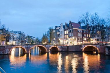 Alacakaranlık süre boyunca, Hollanda Keizersgracht inersection köprü görünümü Amsterdam kanal ve tarihi evler.
