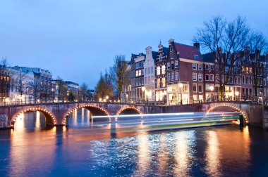 Alacakaranlık süre boyunca, Hollanda Keizersgracht Kavşağı köprü görünümü Amsterdam kanal ve tarihi evler.