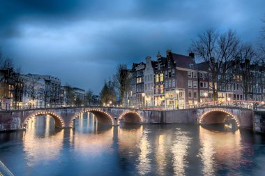 Alacakaranlık süre boyunca, Hollanda Keizersgracht inersection köprü görünümü Amsterdam kanal ve tarihi evler.