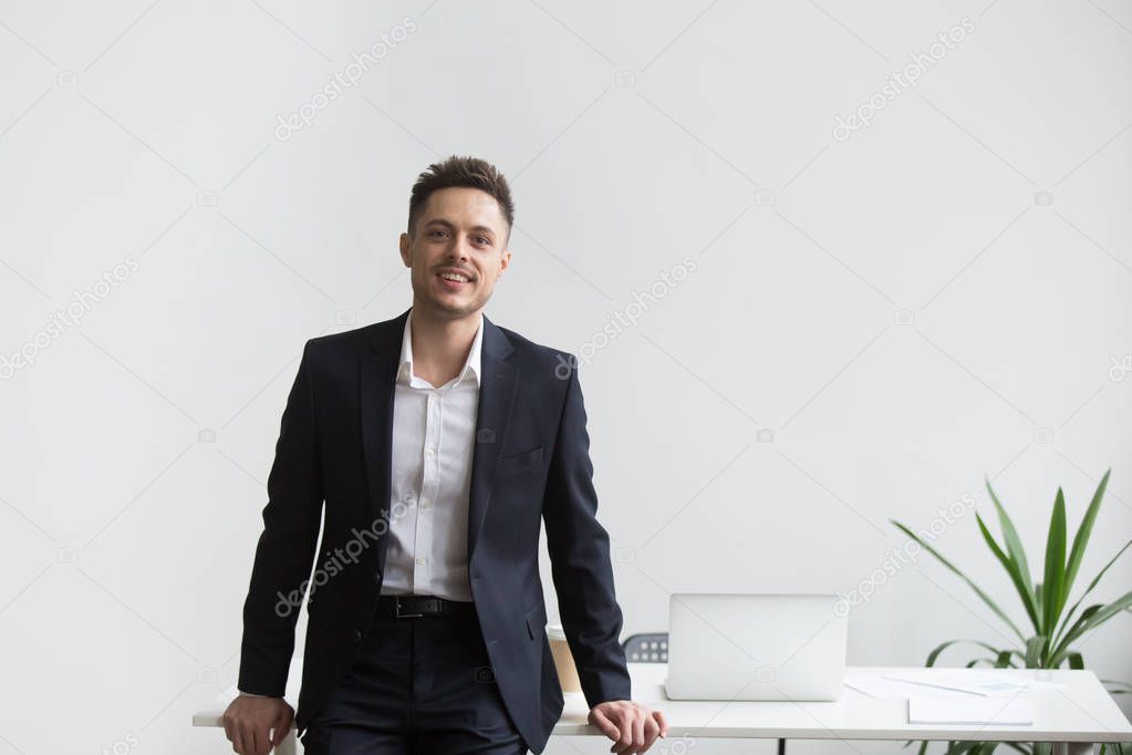 Smiling company CEO posing near office desk