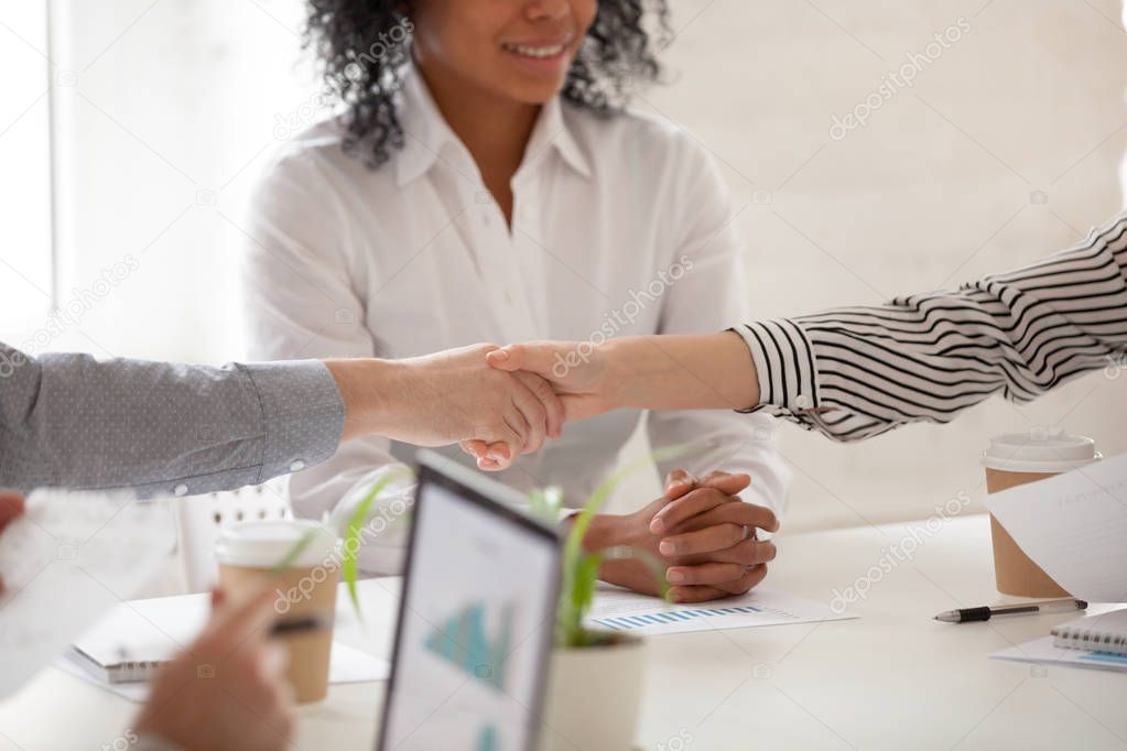 Businessman and businesswoman handshaking at diverse group meeti