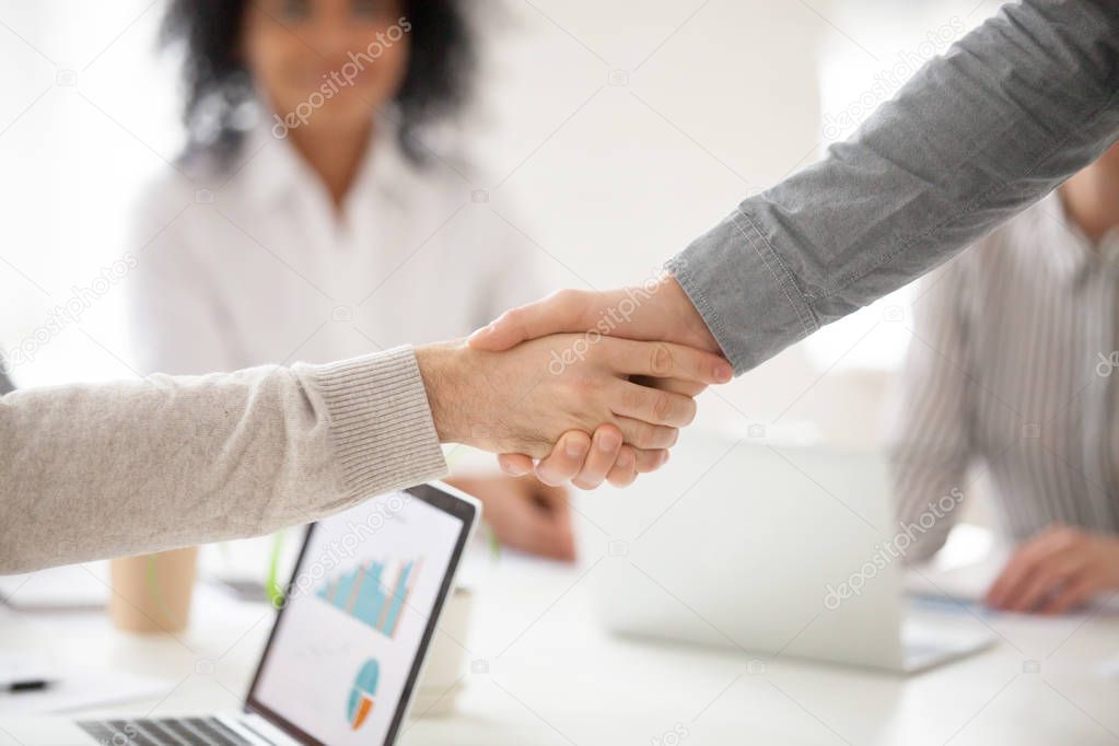 Business partners handshaking at group meeting making project in