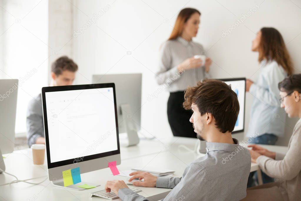 Young male employee working on computer writing email in office