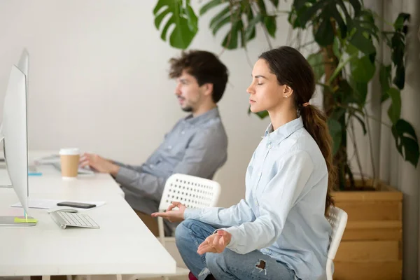 Mindful calm young woman taking break in office for meditation