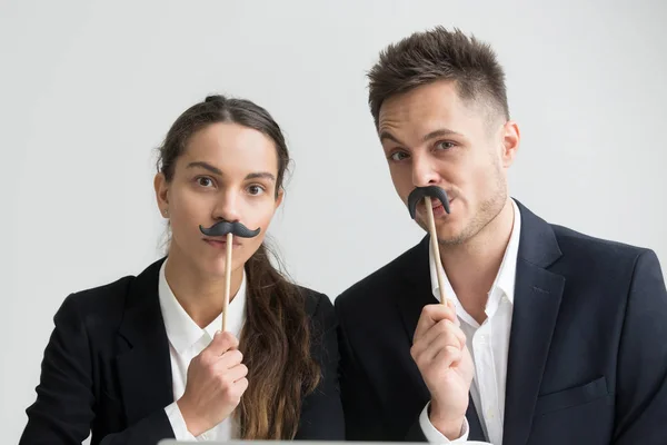 Collèges drôles faisant des visages stupides tenant de fausses moustaches, têtes — Photo