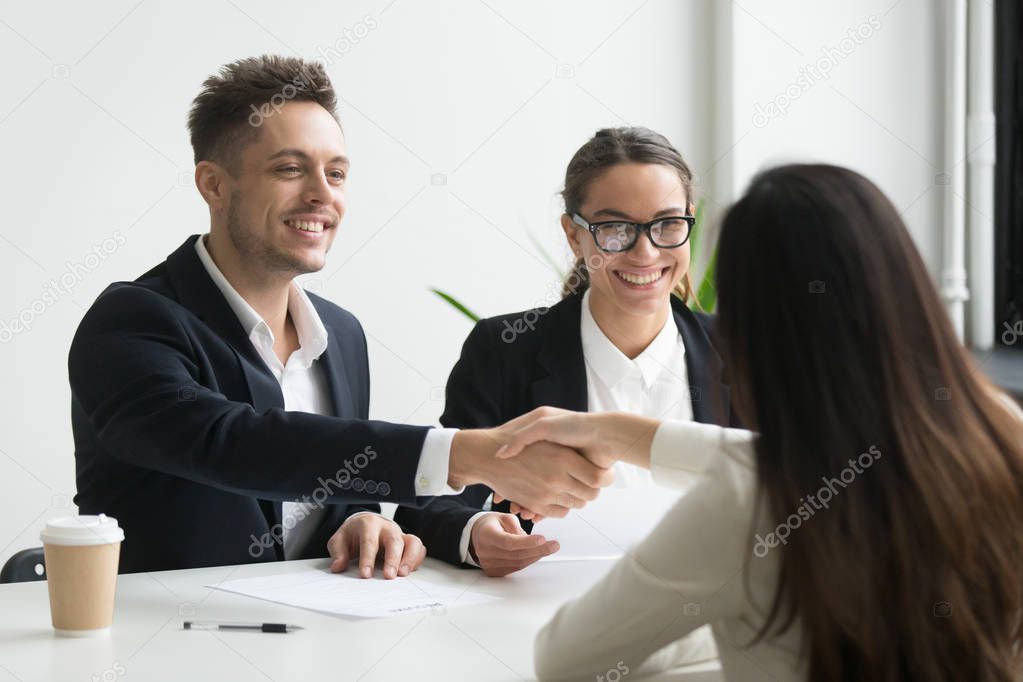 Smiling hr manager handshaking hired female applicant at job int