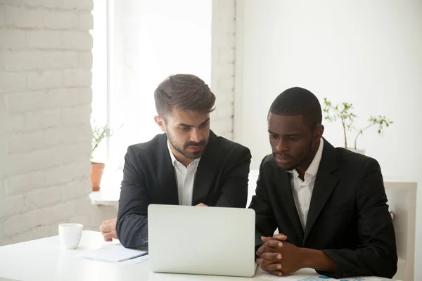 Multiethnic businessmen working together at laptop