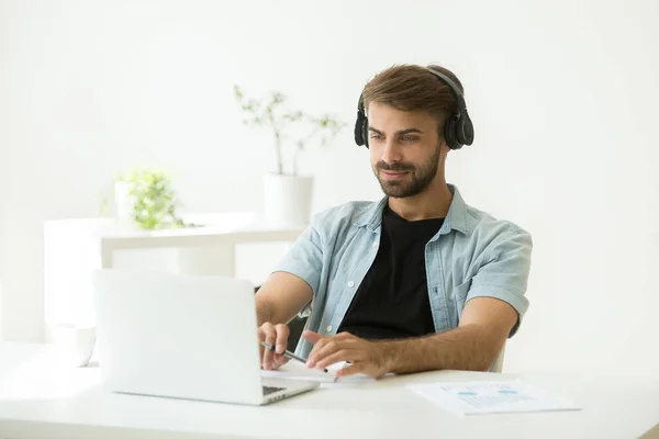 Concentrated worker wearing headphones listening to webinar at l — Stock Photo, Image