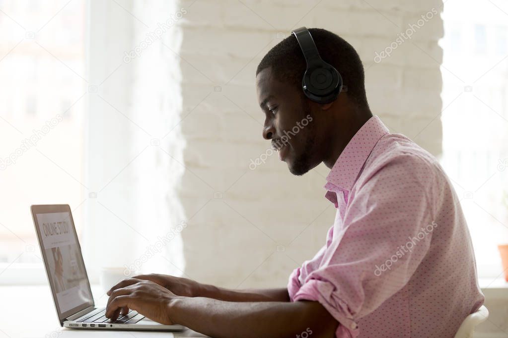 Happy African American in headphones taking online course
