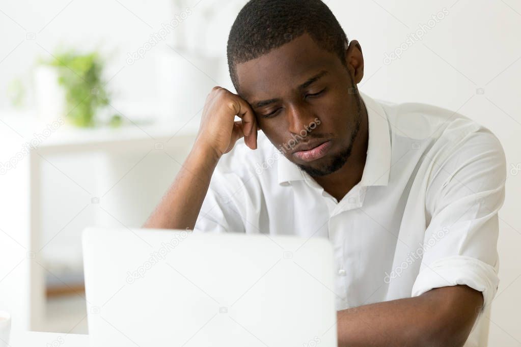 Tired African American worker feeling sleepy in front of laptop