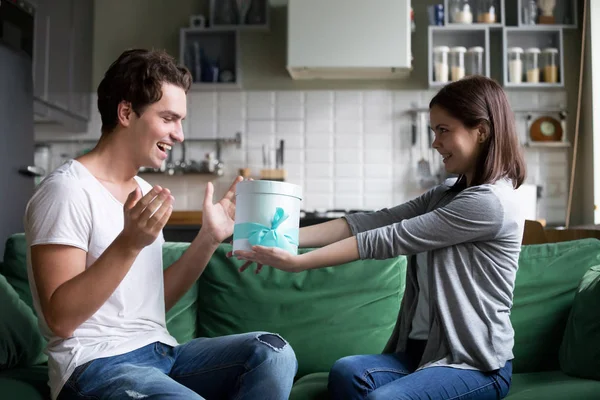 Sonriente chica dando regalo en caja de regalo a novio emocionado — Foto de Stock