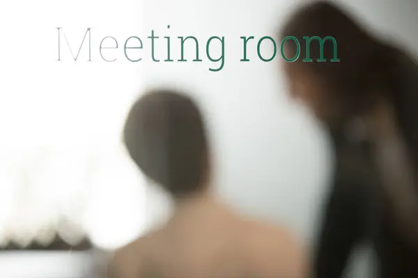 Partners negotiating behind closed glass door of meeting room — Stock Photo, Image