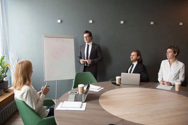 Serious male coach giving presentation on flipchart to business — Stock Photo, Image