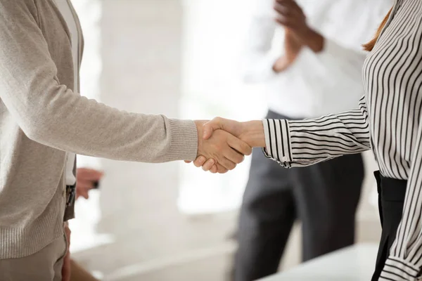 Close up of company CEO leader shaking hand of female employee, congratulating with work achievement, greeting with job promotion. Partners handshaking at business meeting, making deal, negotiating