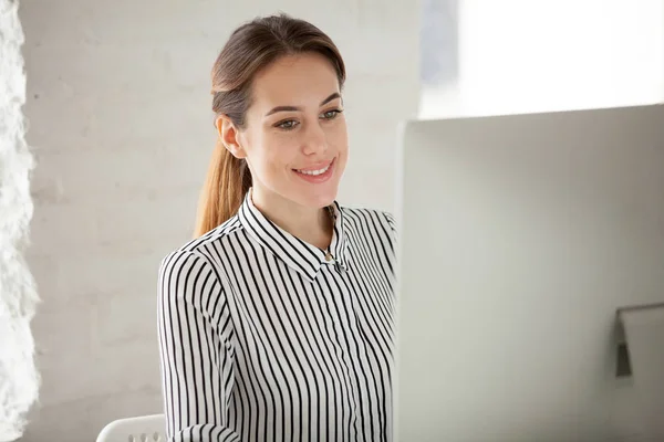 Smiling office worker busy working at desktop computer