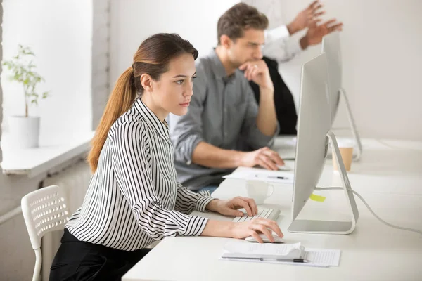 Focused businesswoman writing emails on desktop computer in offi