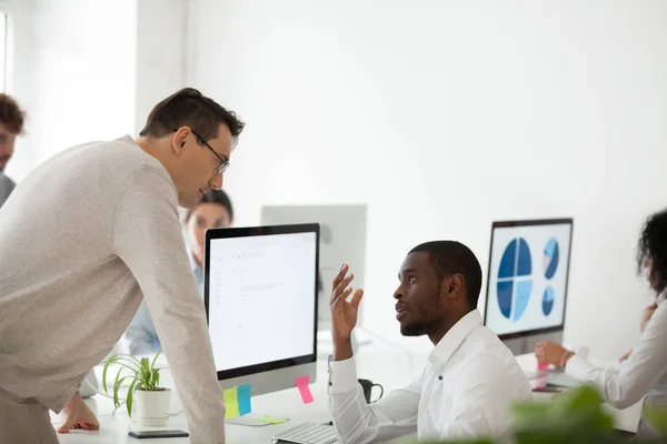 Upset black worker apologizing in front of serious older boss