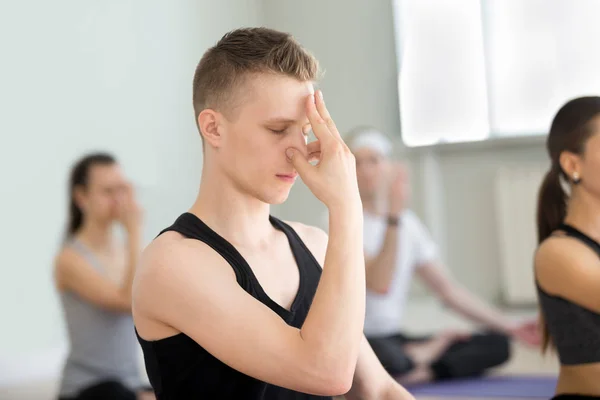 Young man and group of people in nadi shodhana pranayama — Stock Photo, Image