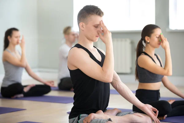 Group of young yogi people practicing Alternate Nostril Breathin