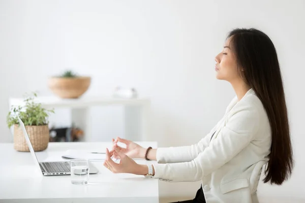 Спокойный азиатский сотрудник медитирует в офисе, снимая стресс на работе — стоковое фото