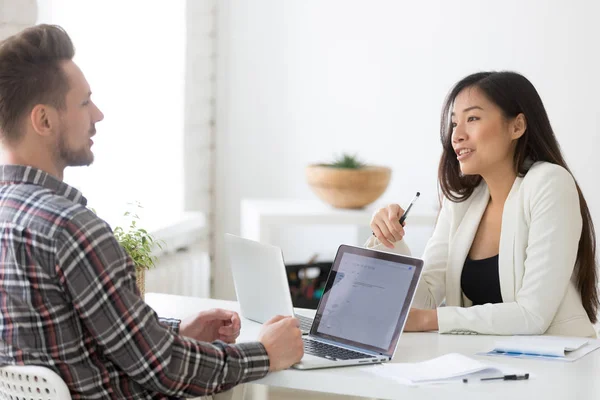 Colleghi amichevoli parlando mentre si lavora ai computer portatili in ufficio — Foto Stock