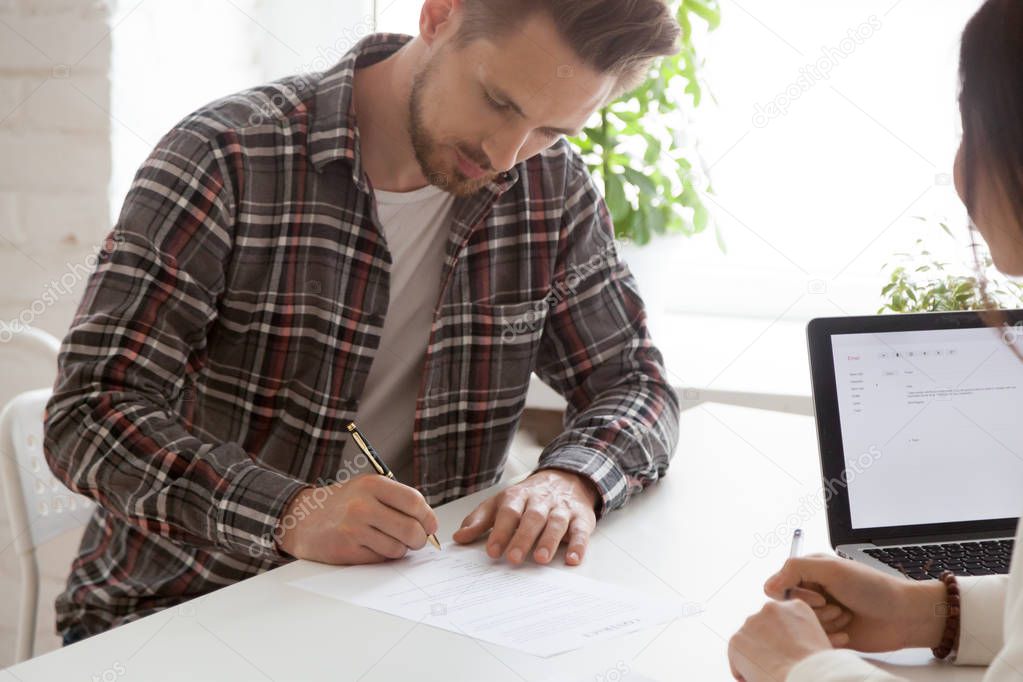 Focused male employee signing work contract after successful int