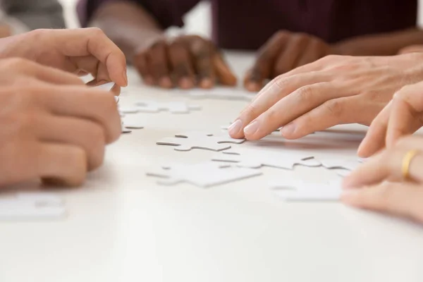 Primer plano de diversos equipos de trabajo ensamblando rompecabezas juntos —  Fotos de Stock