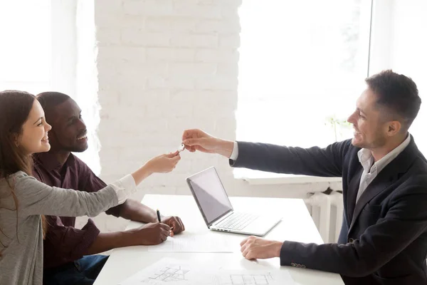 Realtor giving keys to excited multiethnic couple — Stock Photo, Image