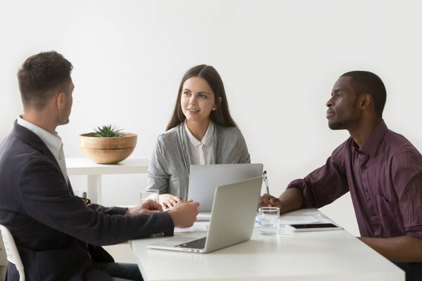 Многорасовые коллеги, работающие над ноутбуками и планшетами
