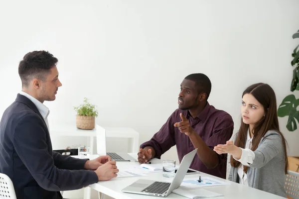 Colegas multirraciales disputando con su compañero de trabajo pidiéndole que lea — Foto de Stock