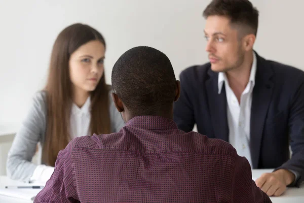 Asesor negro consultando pareja dudosa socios durante las negociaciones — Foto de Stock