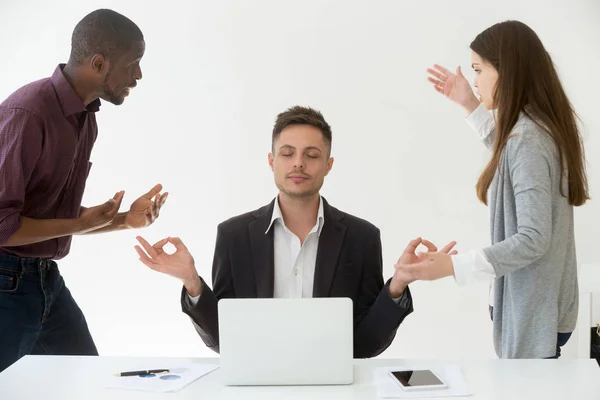 Caucasian employee meditating at workplace ignoring colleagues — Stock Photo, Image