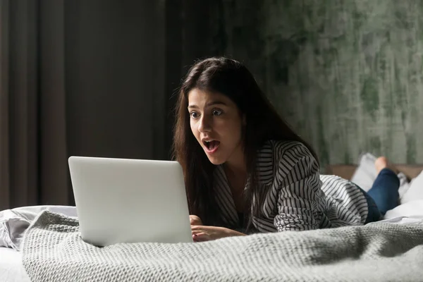 Surprised girl shocked receiving unexpected message at laptop