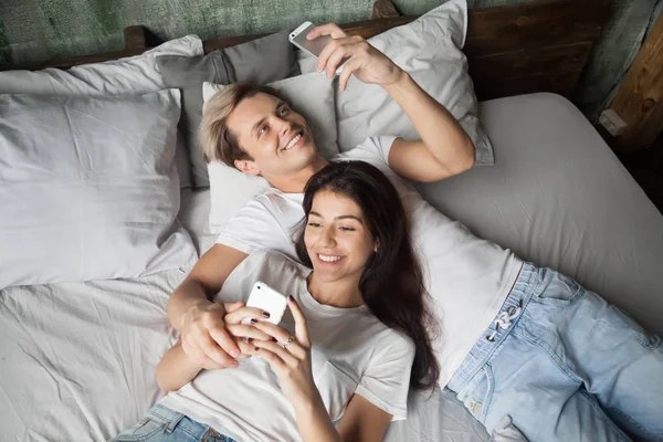 Sonriente pareja milenaria divirtiéndose viendo videos en smartpho — Foto de Stock