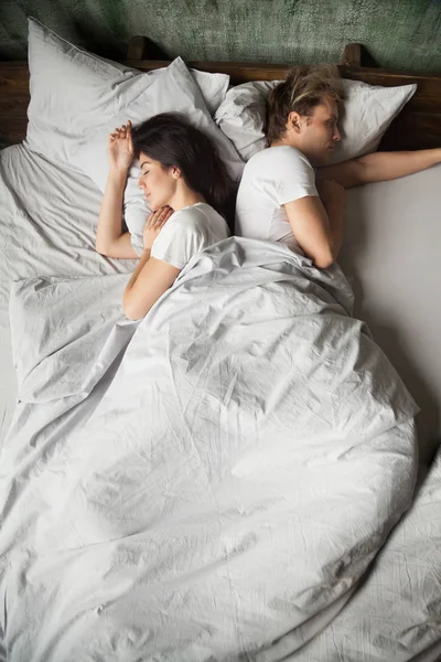 Indifferent millennial couple sleeping back to back after fight — Stock Photo, Image