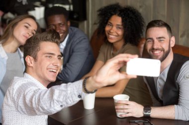 Kafede oturan grup fotoğrafı için gülümseyen çeşitli iş arkadaşları