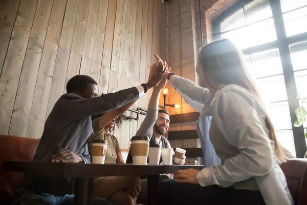 Happy diverse friends giving high five chilling out in cafe — Stock Photo, Image