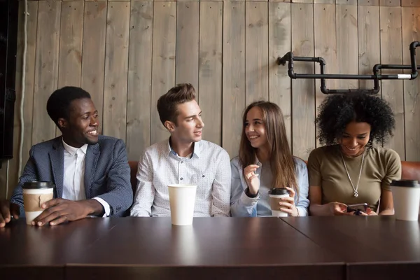 Sonrientes amigos multirraciales tomando café divirtiéndose en la cafetería — Foto de Stock