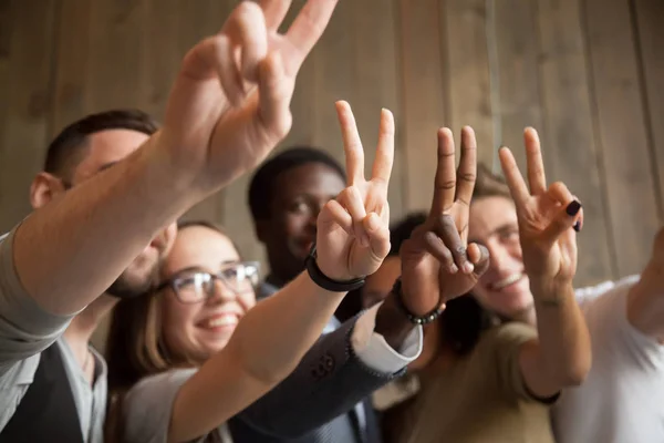 Närbild av leende olika människor visar peace-tecken — Stockfoto