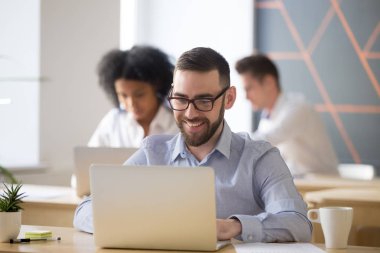 Gülümseyen erkek çalışan dizüstü paylaşılan Office çalışan meşgul