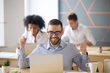Coworking içinde oturan online piyango kazanan erkek işçi heyecanlı 