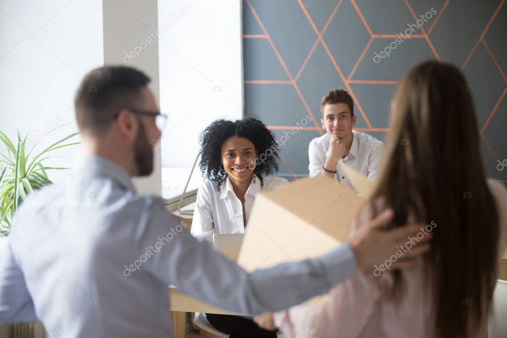 Excited multiracial colleagues welcoming new employee in office