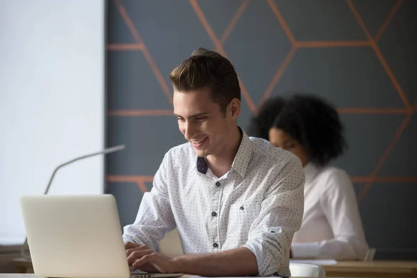 Gelukkig duizendjarige werknemer drukke werken bij laptop in kantoor — Stockfoto