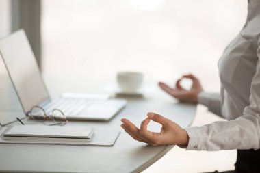 Kadın işçinin iş yerinde lotus pozisyonda meditasyon kapatın
